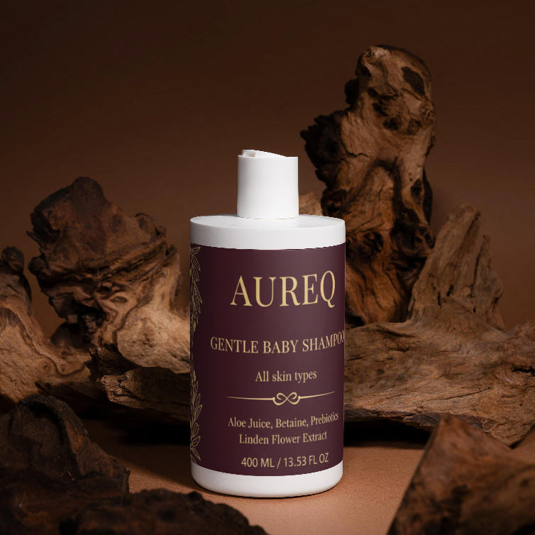 Aureq Gentle Baby Shampoo bottle with a brown label against a wooden background