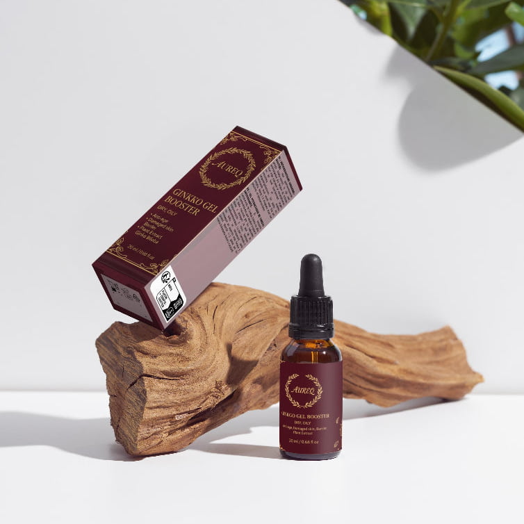 A bottle and box of a product on a wooden block with a white background